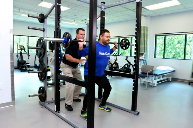 UF Health physical therapist spots a patient performing squats at UF Health Rehabilitation - Emerson