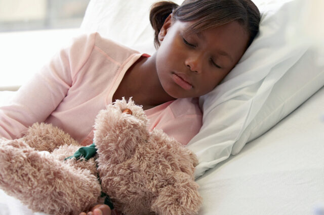 Child with teddy bear sleeping in bed