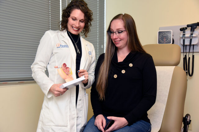 Physical therapist shows patient model of female pelvic region