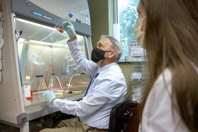UF faculty researcher looks at red vial.