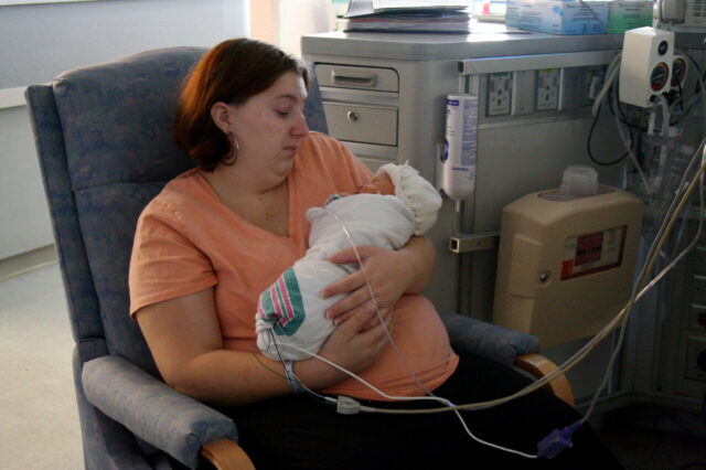 Mother with infant child in neonatal intensive care unit