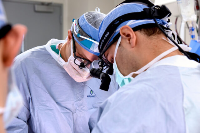 UF Health neurosurgeons in blue scrubs performing a surgery