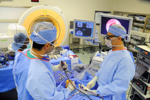 Two neurosurgeons performing a surgical procedure in an operating room.