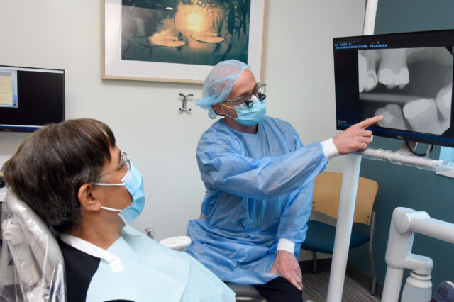 UF Health dentists shows digital x-ray of teeth to patient