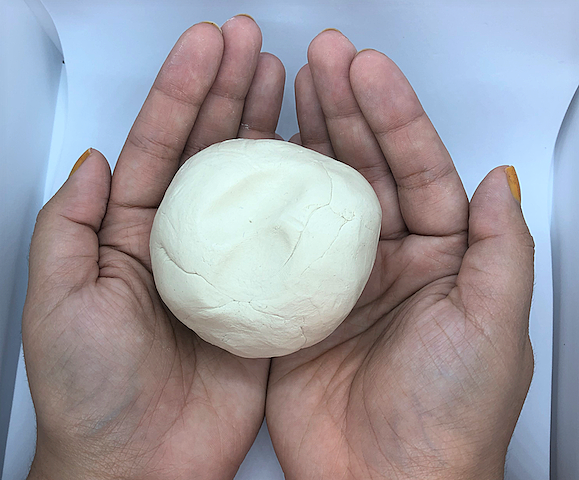 Hands holding round ball of clay