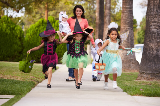 Mother walking with four children in costumes and holding a baby