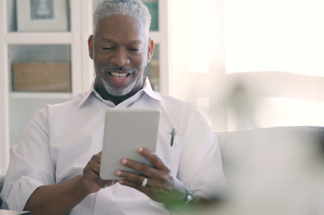 Man smiling and looking at a hand-held digitial tablet