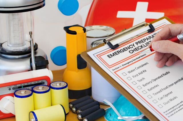 Person holding a pen with a checklist for emergency preparedness