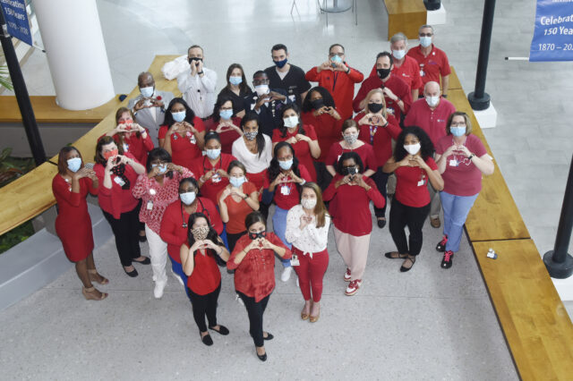 Group of people wearing red making heart shape with hands
