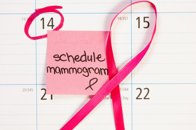 Calendar with date marked in pink and words schedule mammogram with curled pink ribbon