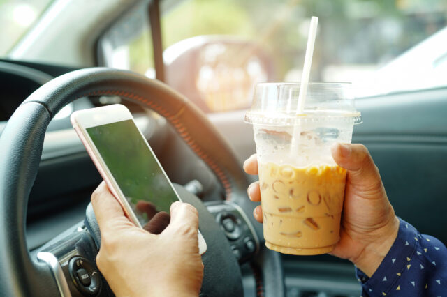 Driver holing a drink cup and a mobile phone
