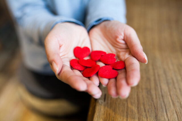 Person's hands outstretched holding small red hearts