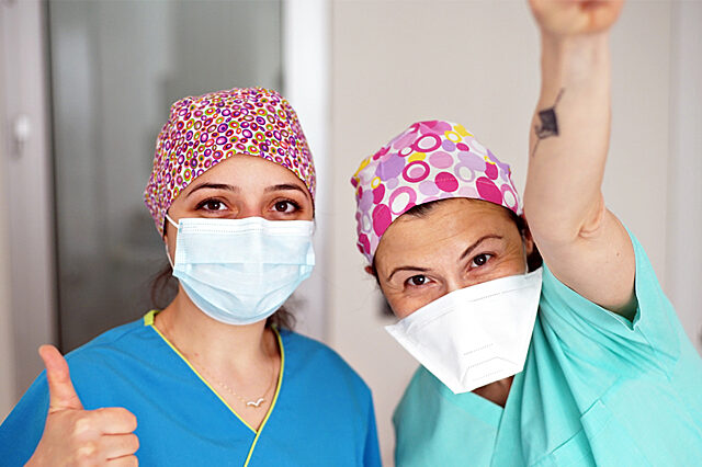Two health care workers in masks giving a thumbs up signal
