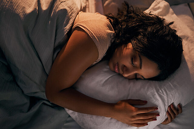 Woman sleeping with pillow on her bed