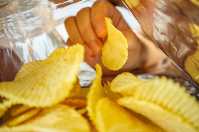 Person's hand picking up potato chips