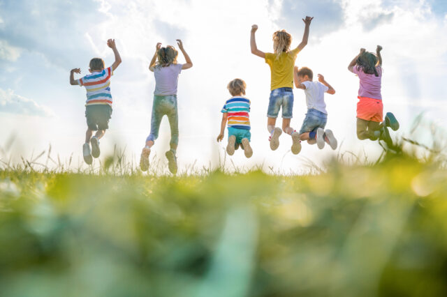 Six children outdoors jumping in the air