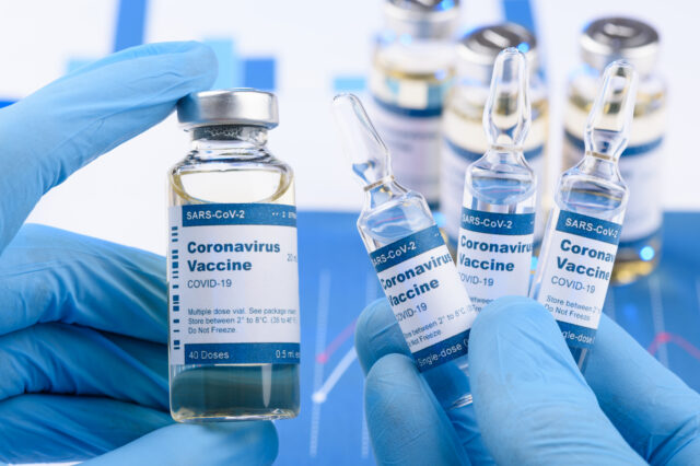 Person with gloves holding vials of the Coronavirus Vaccine