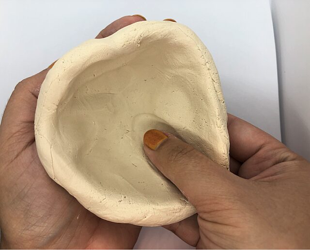 Person shaping bowl with thumb