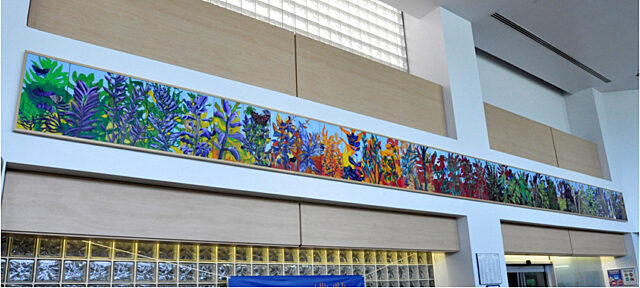 Long multi-colored art with plants, leaves, and butterflies along the top of the room in the healing gardens.